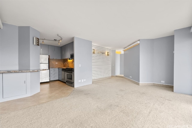 unfurnished living room with rail lighting and light carpet