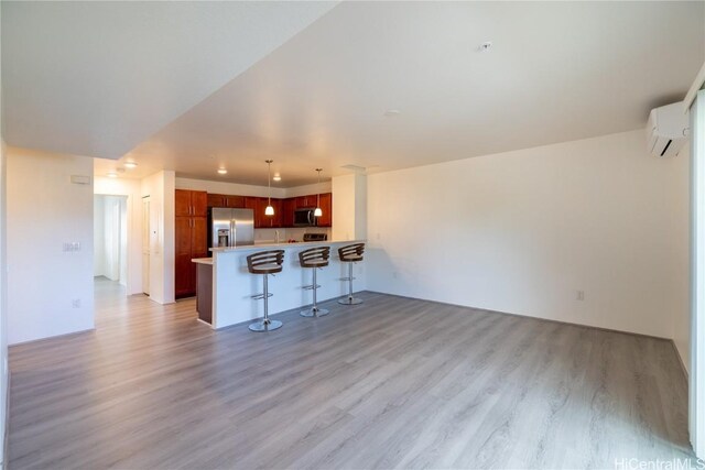 kitchen with a breakfast bar, hanging light fixtures, kitchen peninsula, a wall unit AC, and stainless steel appliances