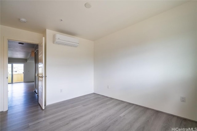 unfurnished room with an AC wall unit and light wood-style flooring