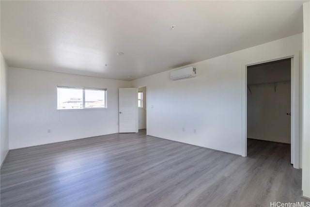 empty room featuring a wall mounted air conditioner and wood finished floors