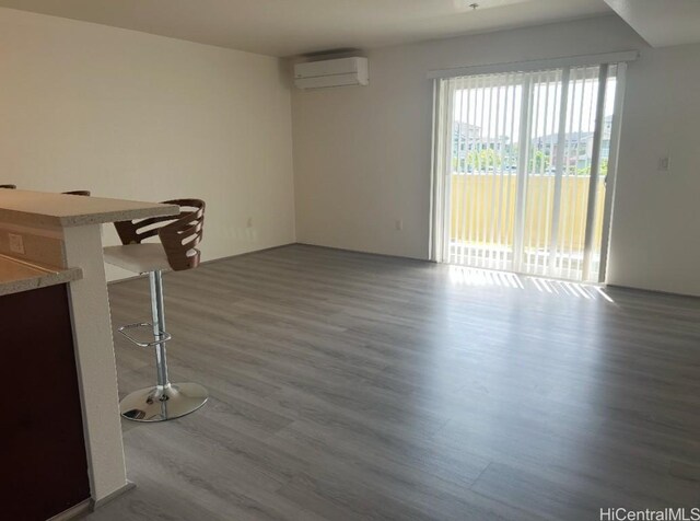 unfurnished living room with hardwood / wood-style floors and an AC wall unit