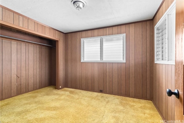 unfurnished bedroom with a closet, wooden walls, and light carpet