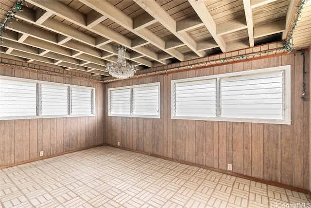 unfurnished room with a chandelier and wood walls