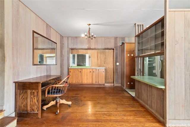 interior space featuring an inviting chandelier, decorative light fixtures, hardwood / wood-style floors, and wood walls