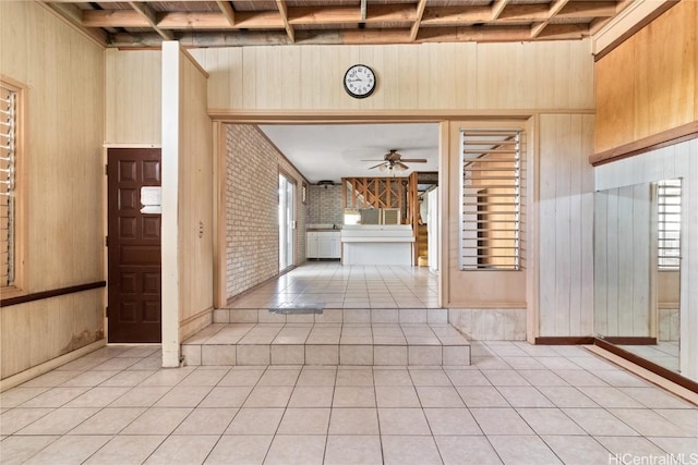 hallway featuring brick wall, light tile patterned floors, and wood walls