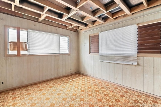 spare room with coffered ceiling and wood walls