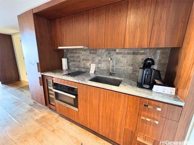 kitchen featuring tasteful backsplash, sink, oven, black electric stovetop, and light stone countertops