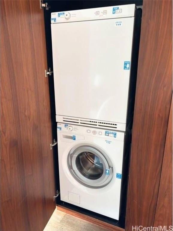 clothes washing area featuring light hardwood / wood-style flooring and stacked washer and clothes dryer