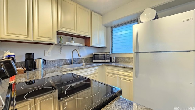 kitchen featuring range with electric cooktop, cream cabinets, sink, and white fridge