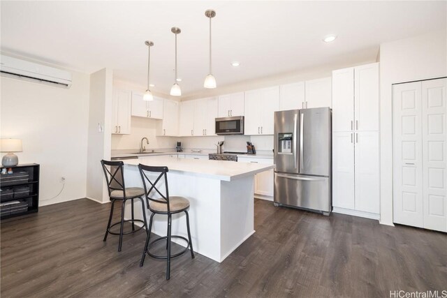 kitchen with pendant lighting, sink, white cabinetry, stainless steel appliances, and a wall mounted air conditioner