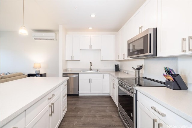 kitchen with pendant lighting, white cabinetry, stainless steel appliances, and an AC wall unit