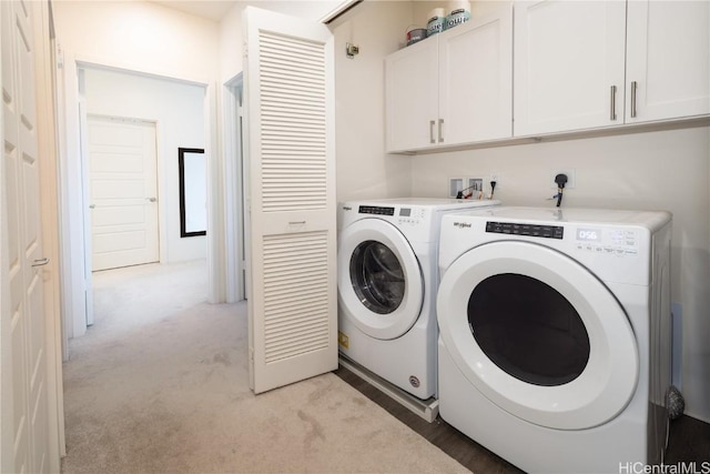 clothes washing area with cabinets, light colored carpet, and independent washer and dryer