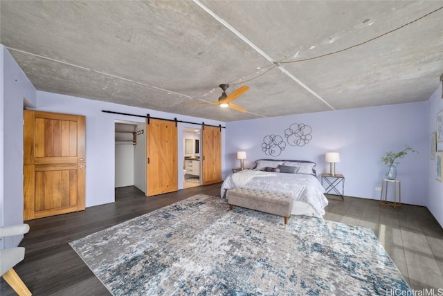 bedroom with dark hardwood / wood-style flooring, a closet, a barn door, and ceiling fan