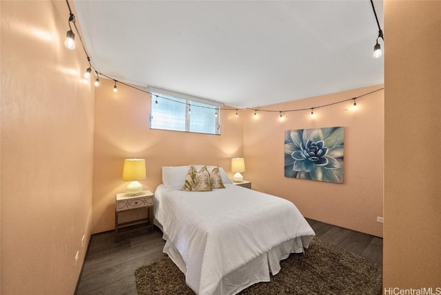 bedroom with track lighting and dark hardwood / wood-style flooring