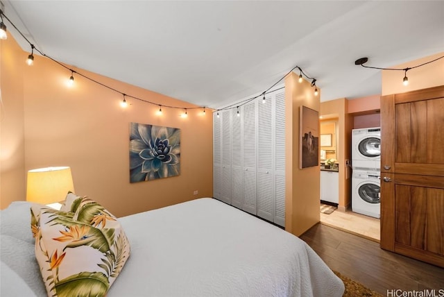 bedroom featuring stacked washer and clothes dryer, dark hardwood / wood-style floors, and a closet