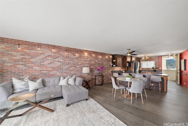 living room featuring ceiling fan, brick wall, and dark hardwood / wood-style flooring