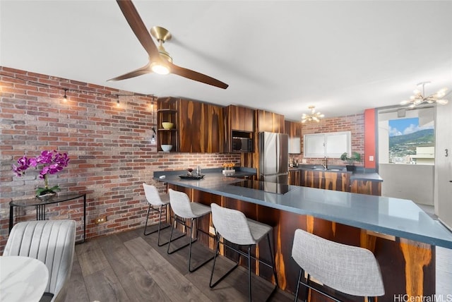 kitchen with a breakfast bar, sink, stainless steel refrigerator, and kitchen peninsula