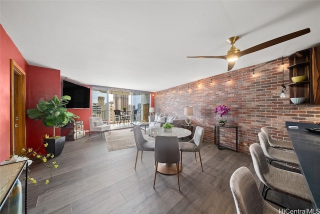 dining area featuring ceiling fan, brick wall, and wood-type flooring