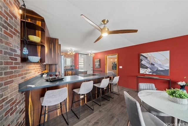 kitchen featuring brick wall, a breakfast bar, dark hardwood / wood-style floors, kitchen peninsula, and black electric cooktop