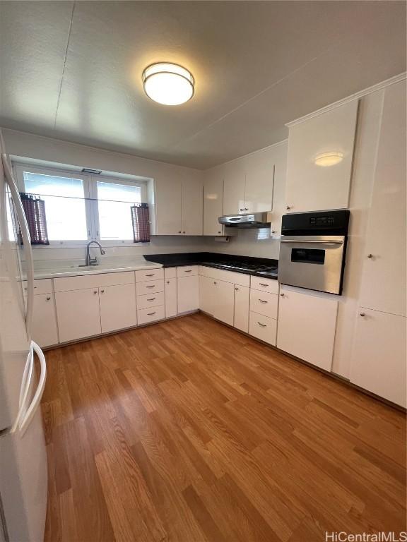 kitchen featuring white cabinetry, stainless steel appliances, sink, and light wood-type flooring