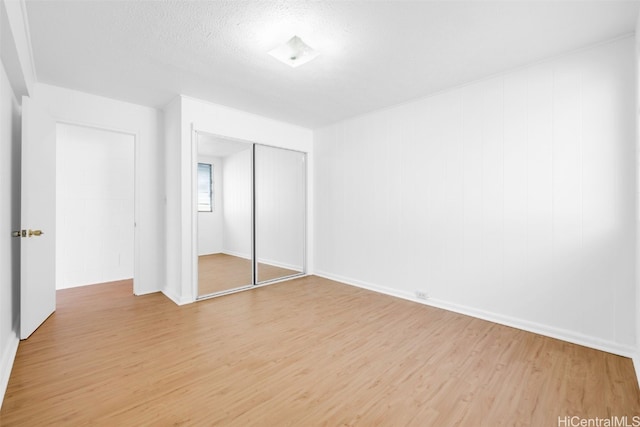 unfurnished bedroom featuring a closet, a textured ceiling, and light wood-type flooring