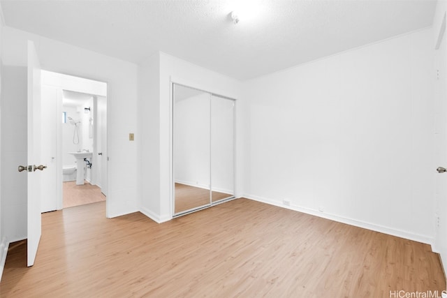 unfurnished bedroom featuring light hardwood / wood-style flooring, a closet, and a textured ceiling