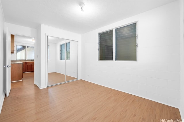 unfurnished bedroom featuring a closet, a textured ceiling, and light hardwood / wood-style flooring