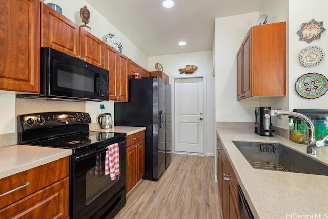 kitchen with sink, light hardwood / wood-style flooring, and black appliances