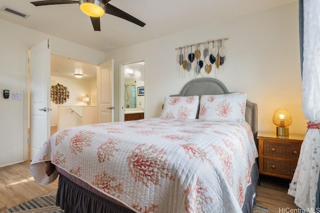 bedroom with wood-type flooring, ceiling fan, and ensuite bath