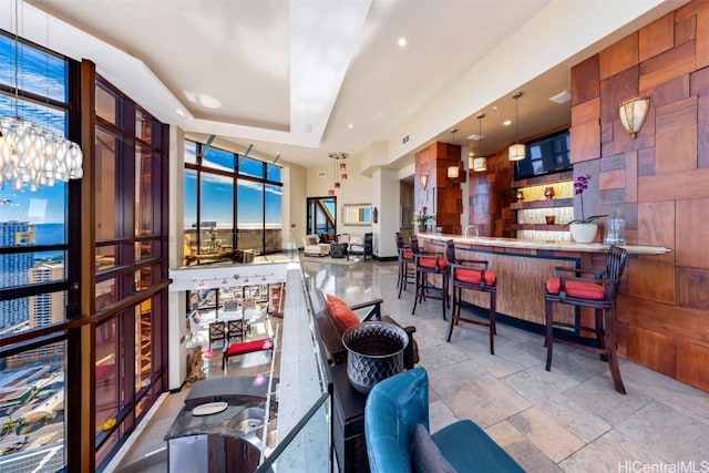 bar featuring a tray ceiling, decorative light fixtures, and expansive windows