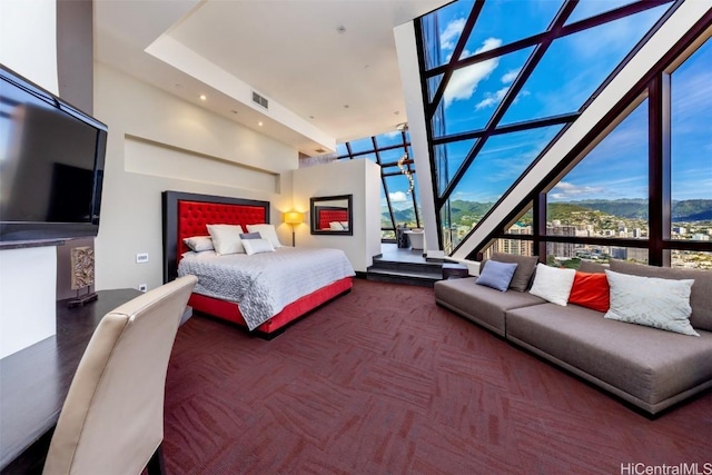 bedroom featuring a mountain view, a towering ceiling, carpet floors, and a wall of windows