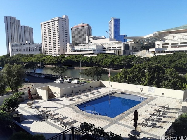 view of pool featuring a water view and a patio