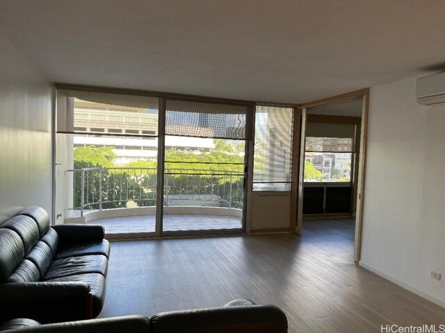 living room featuring a wall of windows, wood-type flooring, and a wall mounted AC