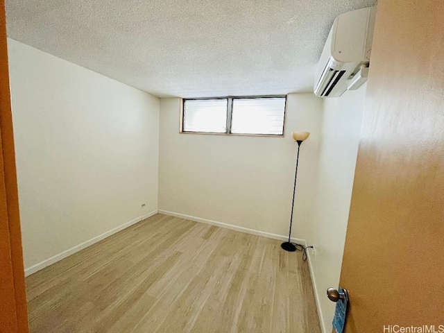 1717 Ala Wai Blvd Unit 505, Honolulu, HI 96815 - empty room featuring a wall mounted air conditioner, light wood finished floors, and a textured ceiling