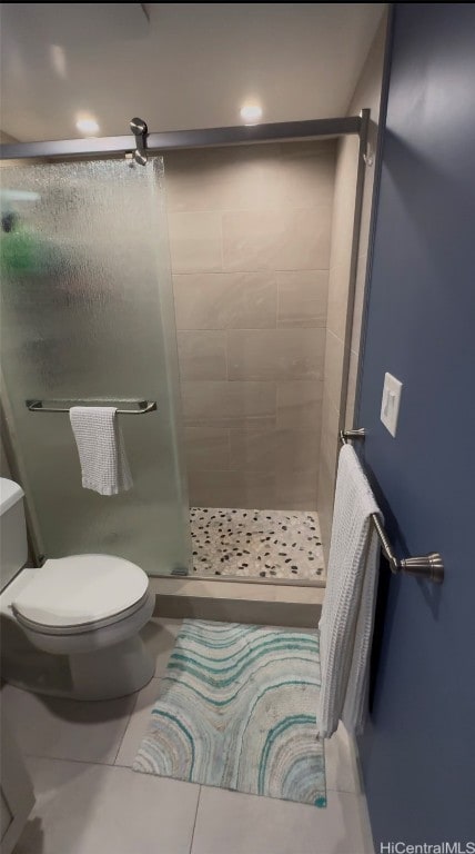 bathroom with tile patterned flooring, tiled shower, and toilet