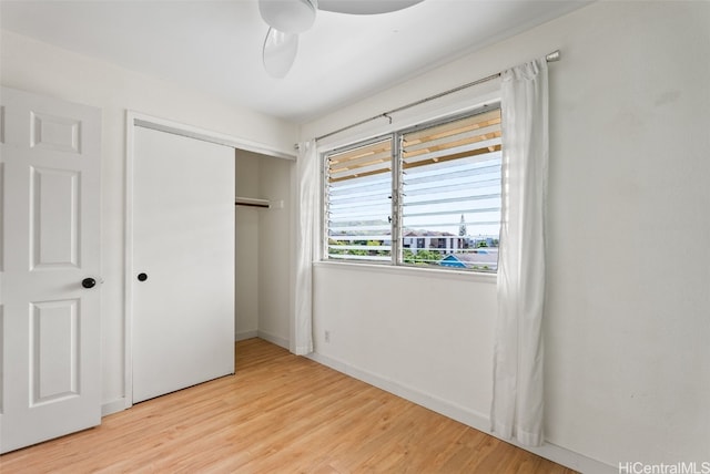 unfurnished bedroom with light wood-style flooring, baseboards, ceiling fan, and a closet