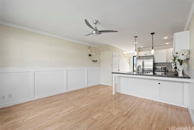 kitchen featuring light wood finished floors, white cabinets, dark countertops, appliances with stainless steel finishes, and a peninsula