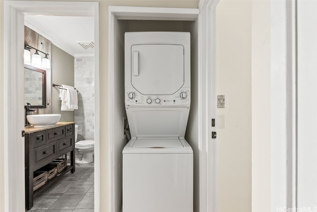 clothes washing area with laundry area, a sink, visible vents, stacked washer / drying machine, and crown molding