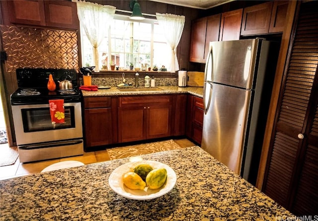 kitchen with stainless steel appliances, tasteful backsplash, a sink, and light stone countertops