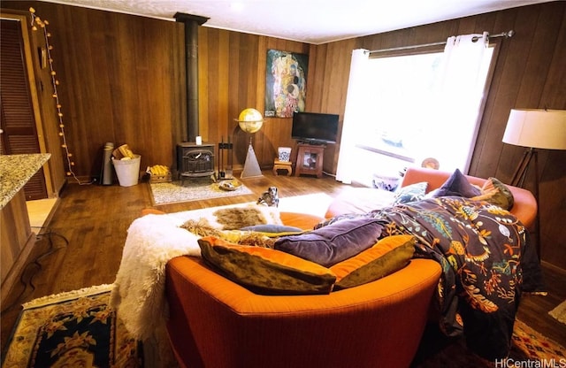 living room with wood-type flooring, wooden walls, and a wood stove