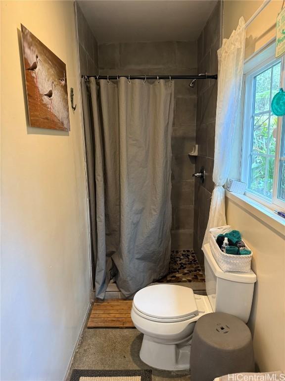 bathroom featuring toilet and a stall shower