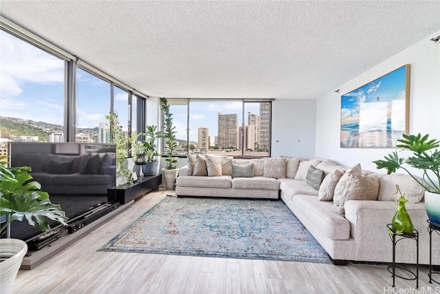 living room with a wall of windows, a textured ceiling, and light wood-type flooring