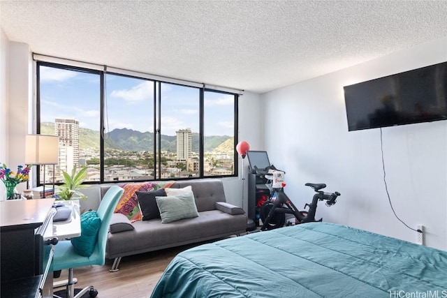 bedroom featuring floor to ceiling windows, a textured ceiling, and light wood-type flooring