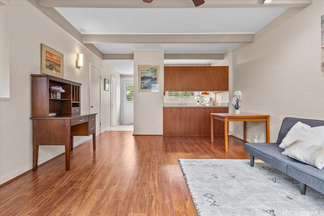 sitting room featuring ceiling fan, wood-type flooring, sink, and beamed ceiling