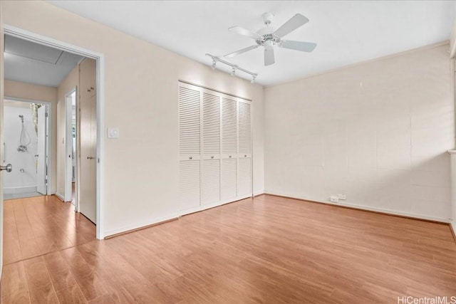 unfurnished bedroom featuring ceiling fan, a closet, track lighting, and light hardwood / wood-style flooring