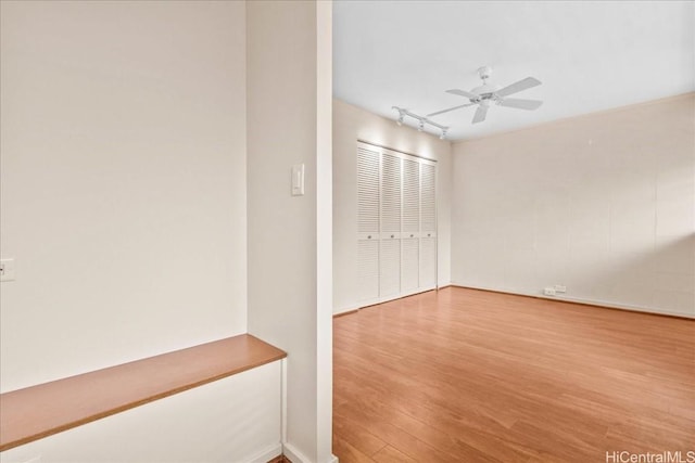 empty room featuring hardwood / wood-style flooring, track lighting, and ceiling fan