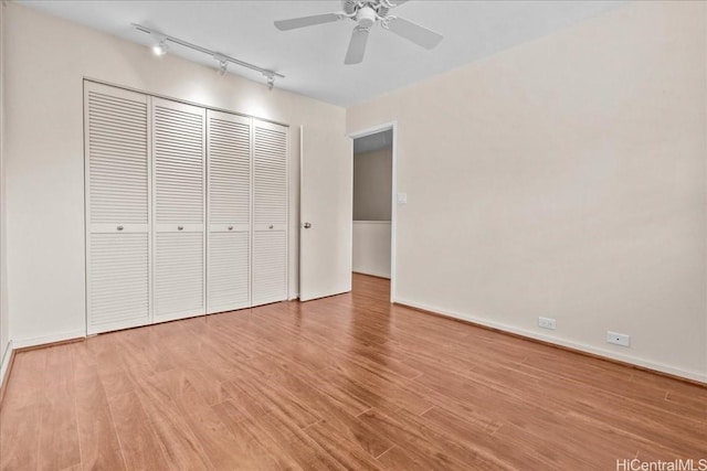 unfurnished bedroom with track lighting, light hardwood / wood-style floors, a closet, and ceiling fan