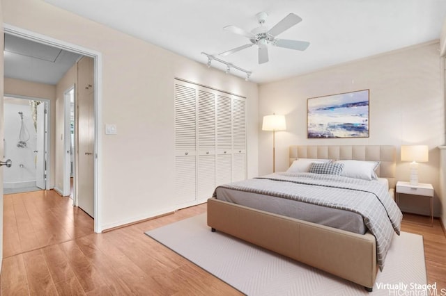 bedroom with hardwood / wood-style flooring, ceiling fan, rail lighting, and a closet