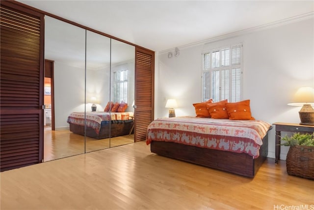 bedroom featuring ornamental molding, light hardwood / wood-style floors, and a closet