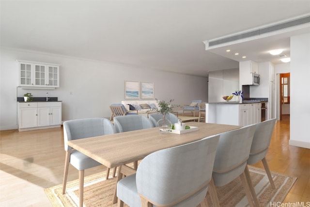 dining space featuring bar and light hardwood / wood-style flooring